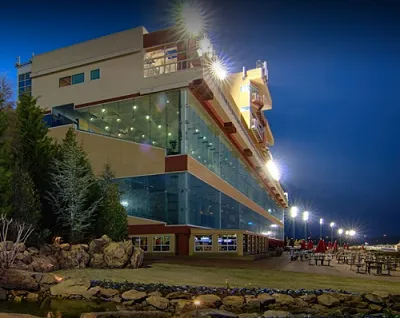 Night view of a modern hotel with large glass windows and outdoor seating, illuminated by lights.