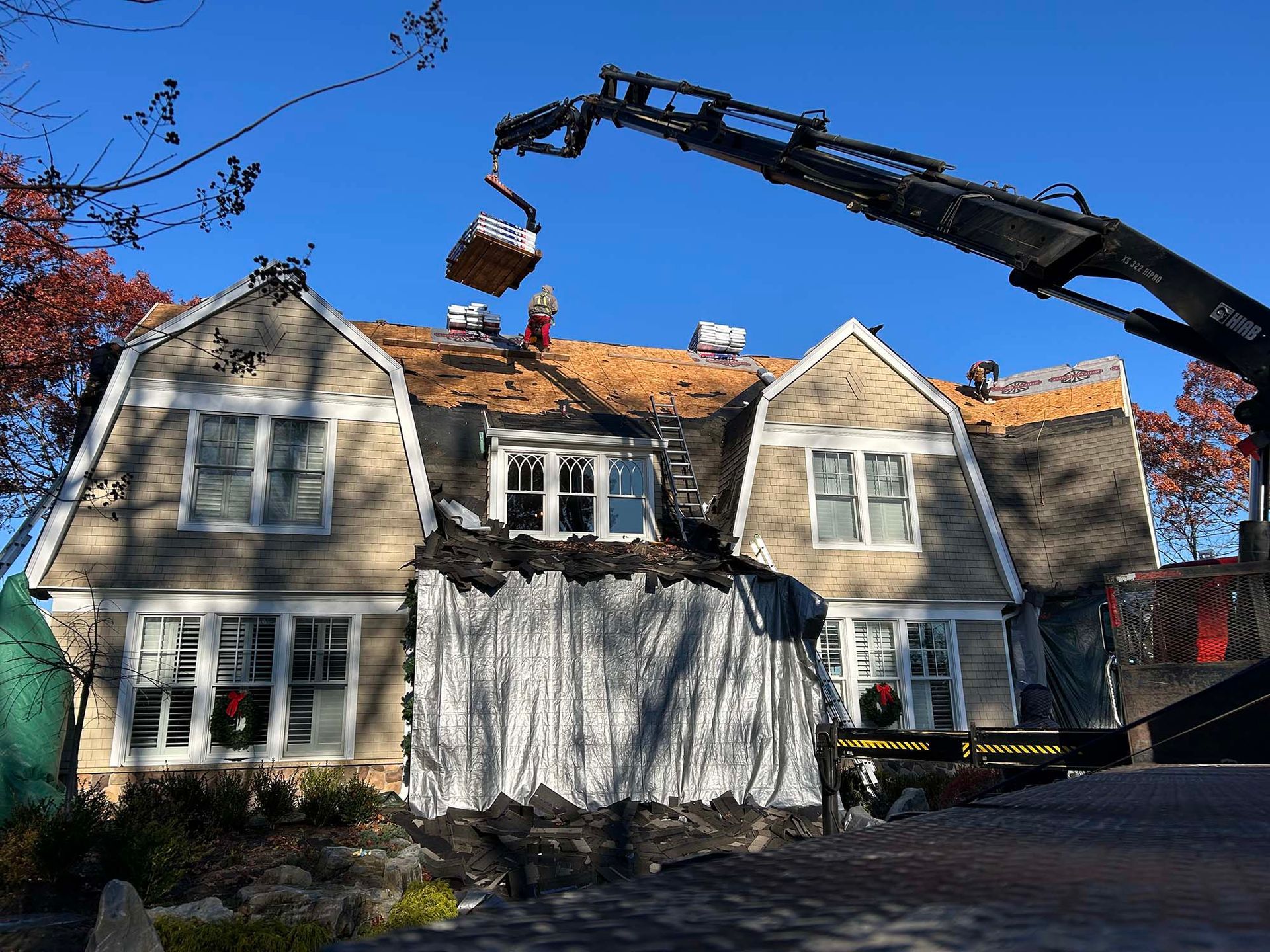 A house under renovation with a crane removing debris from the roof.