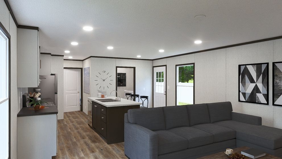 Modern open-plan living room with gray sofa, kitchen island, wood floors, and black-and-white wall art