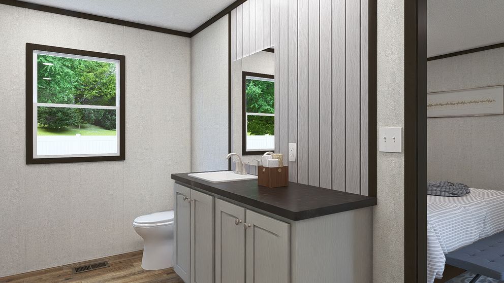 Compact bathroom with vanity, toilet, and window beside a bedroom doorway.
