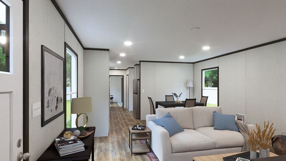 Bright modern living room with a white sofa, recessed lights, wood floor, and open view to a hallway and dining area