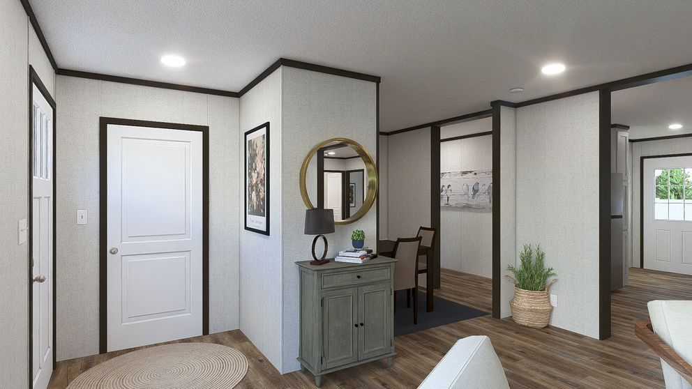 Modern hallway with white doors, gray console table, round mirror, and wood flooring with potted plant.