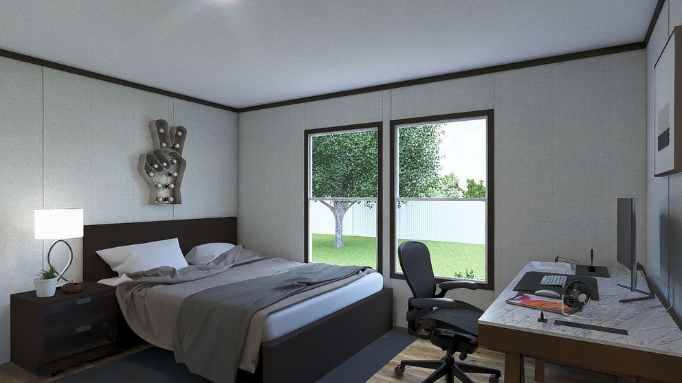 Modern bedroom with gray bed, desk, chair, and large windows overlooking a green yard.