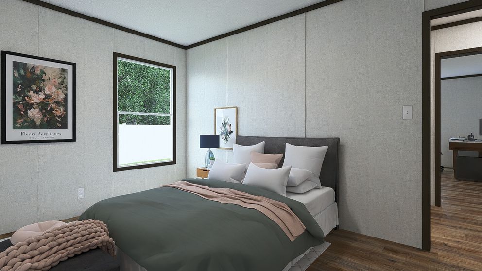 Cozy bedroom with a made bed, framed wall art, window, bedside lamp, and open doorway.
