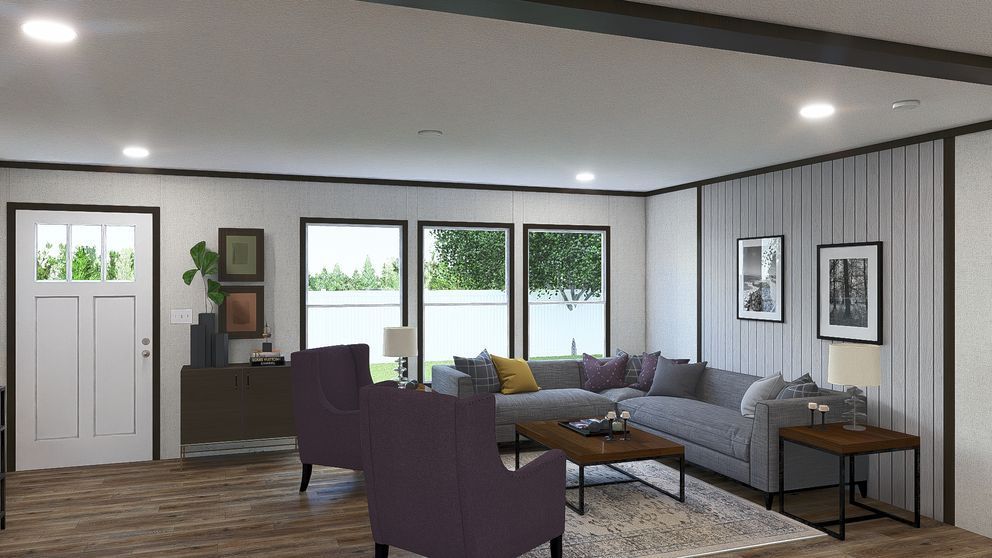 Modern living room with gray sectional, purple chairs, wood floor, and large windows overlooking greenery