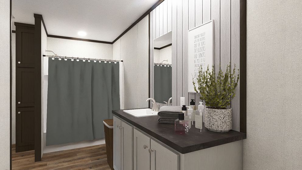Modern bathroom with double vanity, large mirror, gray shower curtain, and wood-look floor.