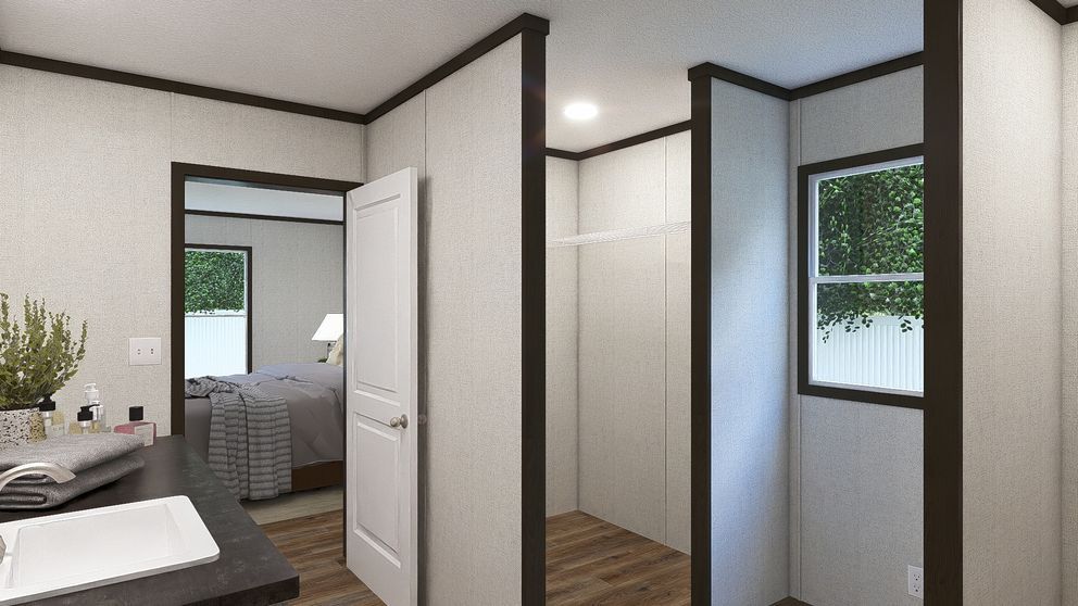 Modern bedroom and bath area with white walls, dark trim, open door, and window light.