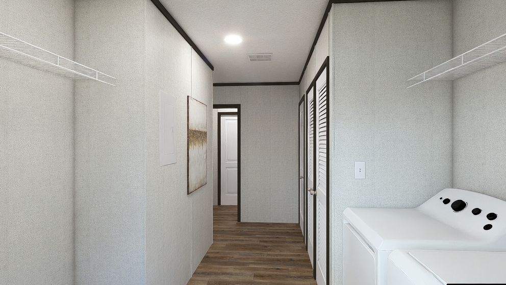 Narrow hallway with white walls and wood floor, showing a laundry area and doorway at the end.