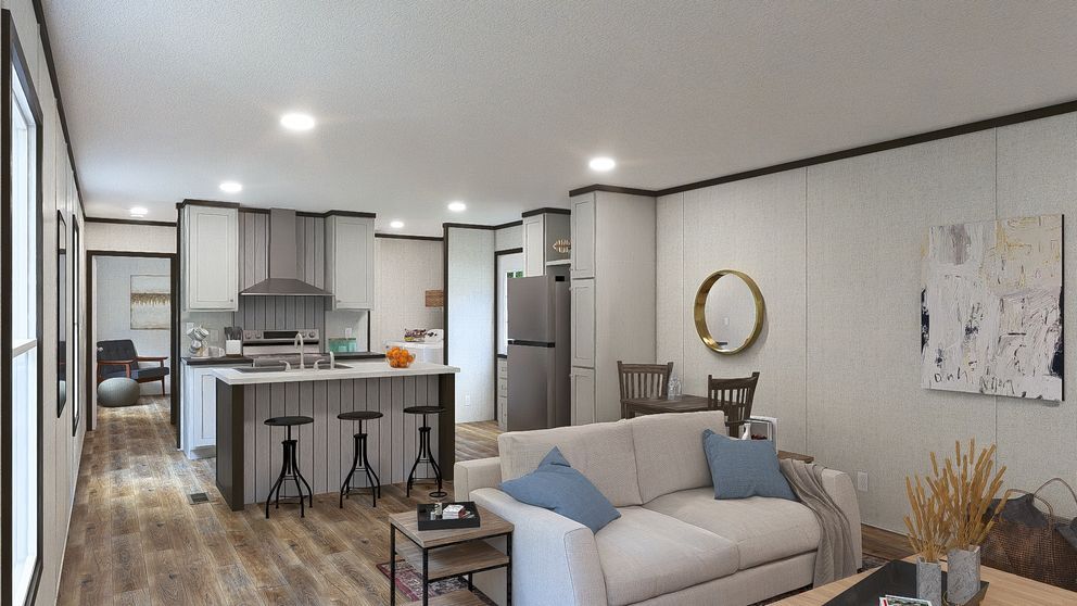 Modern open-plan living room and kitchen with gray sofa, island stools, and warm wood floors