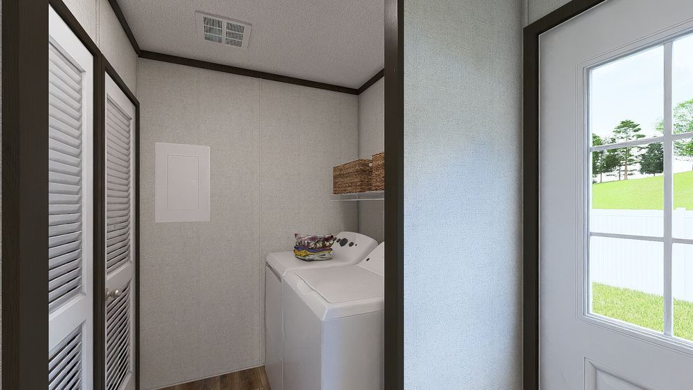 Small laundry room with washer, shelves, and louvered doors beside a bright entryway