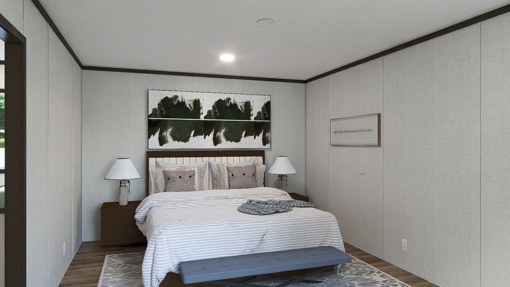 Modern bedroom with a bed, nightstands, lamps, and wall art against white walls.