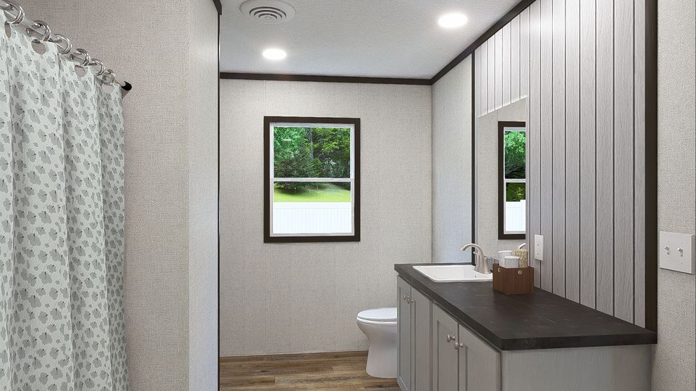 Modern bathroom vanity with mirror, toilet, shower curtain, and two small windows overlooking greenery
