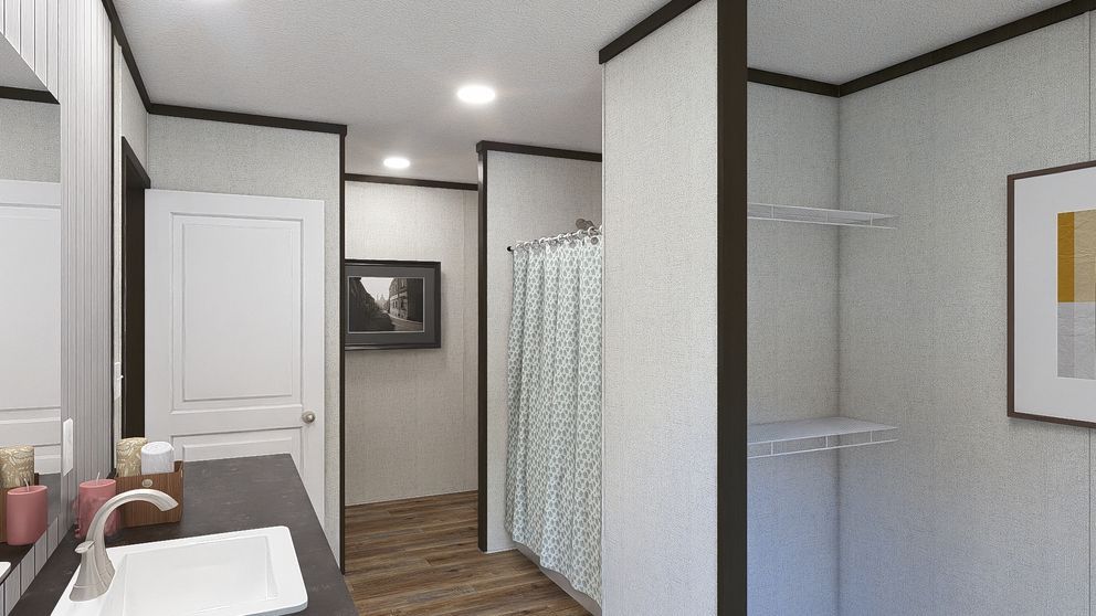 Small bathroom with sink, mirror, shower curtain, wall shelves, and wood flooring.
