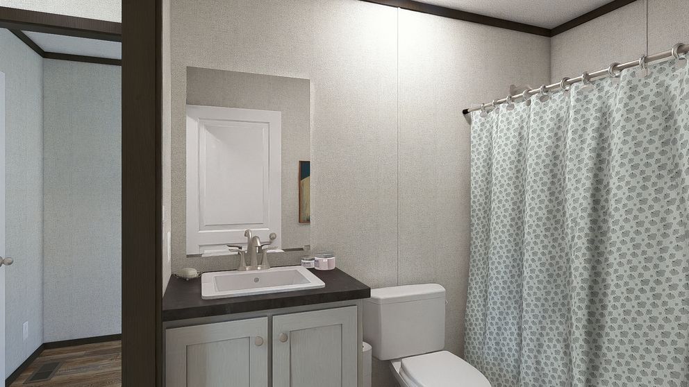 Small bathroom with white sink, toilet, mirror, and patterned shower curtain.