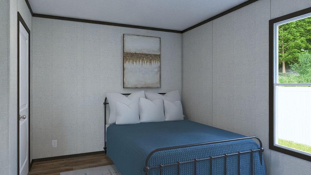 Small bedroom with a blue bed, white walls, framed art, and a window showing greenery.