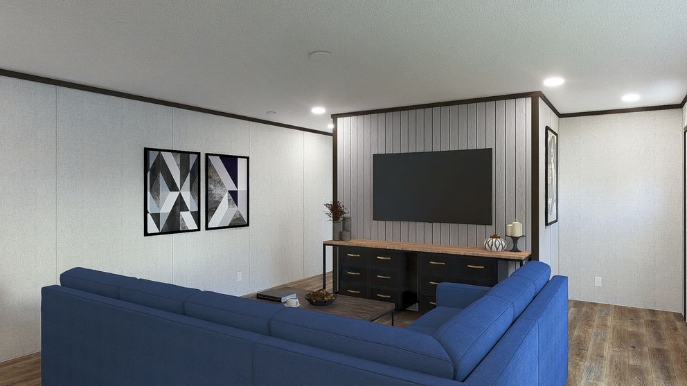 Modern living room with blue sectional sofa, wall-mounted TV, and framed geometric art