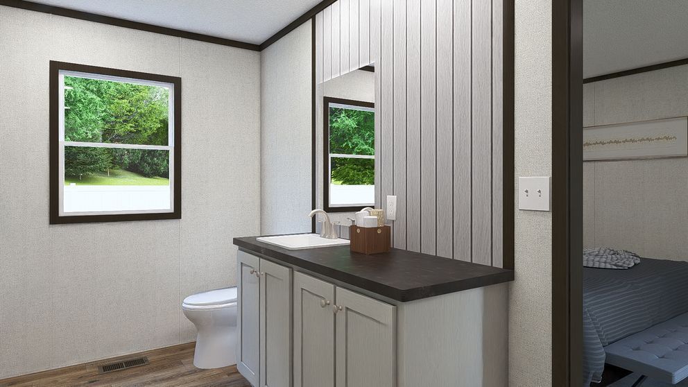 Small bathroom with white walls, dark vanity, window, toilet, and a bedroom visible through the open doorway.