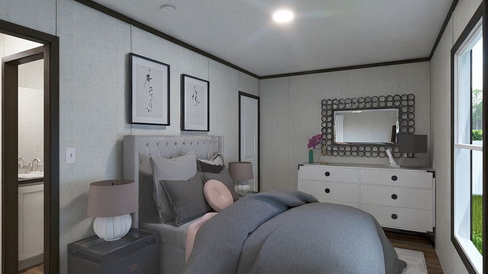 Cozy bedroom with gray bedding, framed wall art, white dresser, and a large window.