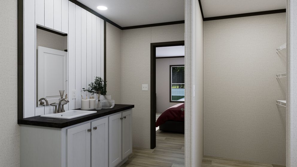 Bright bathroom vanity with sink and mirror opening to a bedroom through a doorway