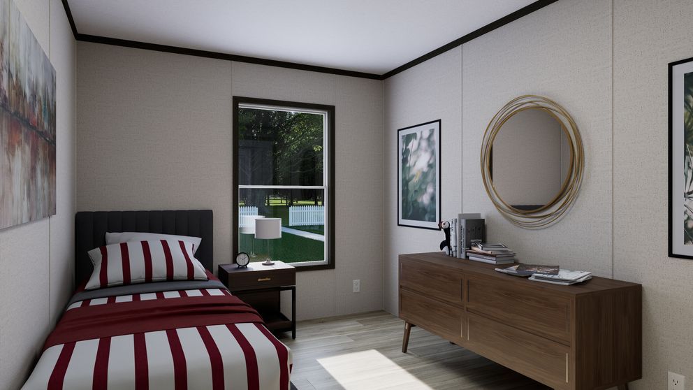 Small bedroom with a striped bed, wooden dresser, round mirror, and window overlooking greenery.