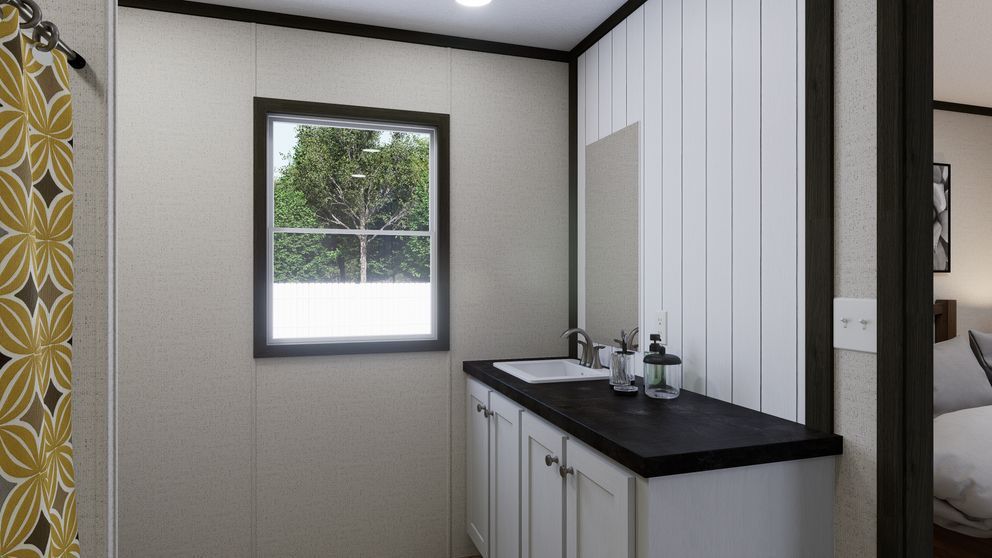 Modern bathroom vanity with black countertop, white cabinets, and a small window above the sink.