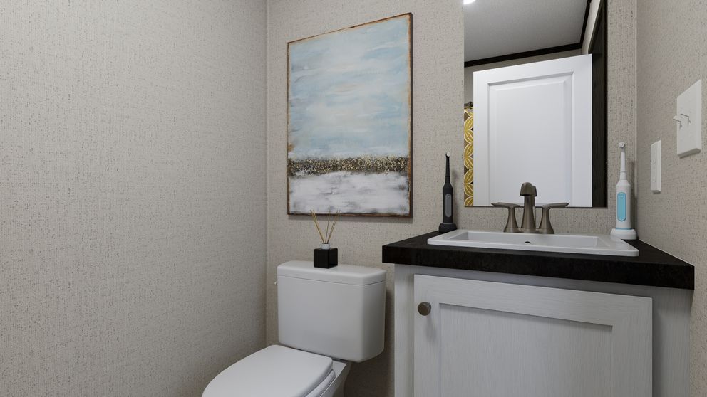 Small bathroom with toilet, white vanity, sink, mirror, and seaside wall art.