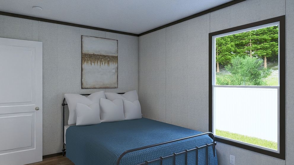 Small bedroom with a blue bed, white door, wall art, and a large window showing greenery outside.
