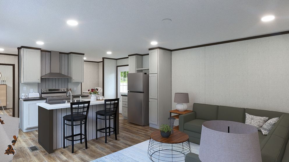 Modern open-concept living room and kitchen with gray sofa, island stools, and stainless steel appliances