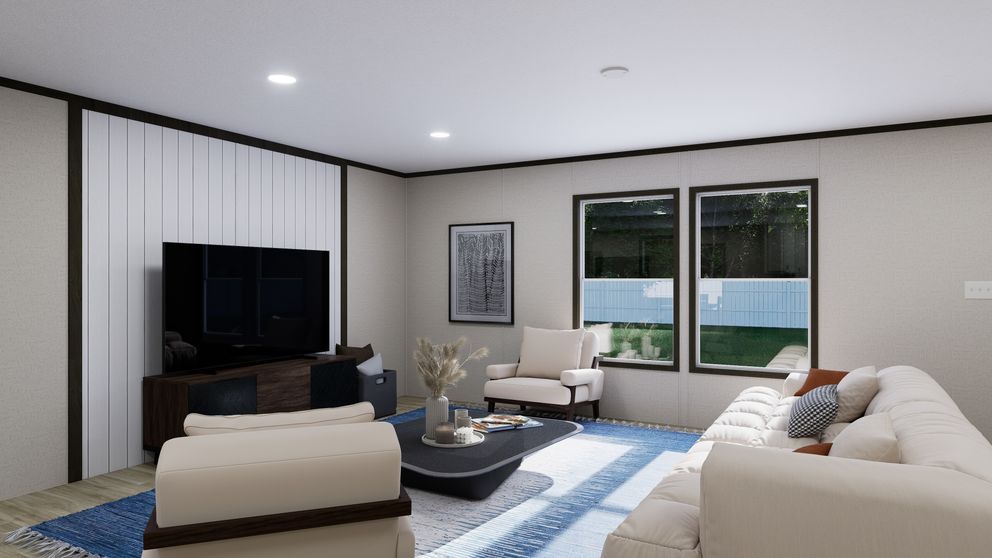 Modern living room with beige sofas, black TV, coffee table, and large windows overlooking a fence.
