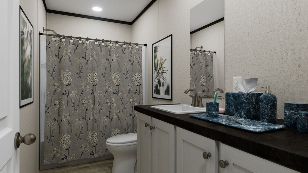 Bathroom with shower curtain, white vanity, dark countertop, and blue decorative jars.