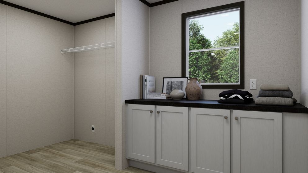 Empty room with white cabinets, black countertop, and a window overlooking trees