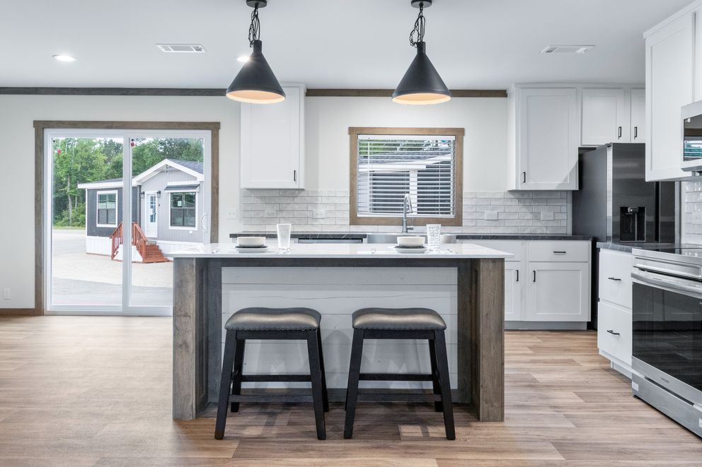 Modern white kitchen with island, pendant lights, and sliding glass door to backyard