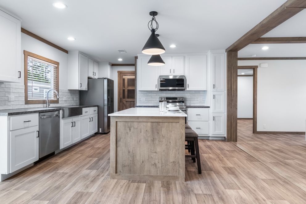 Modern white kitchen with gray cabinets, wood island, pendant lights, and hardwood floors