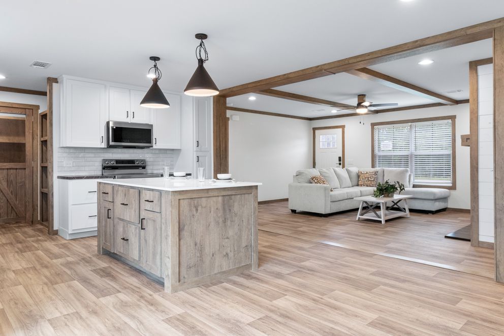 Open-concept kitchen and living room with wood floors, white furniture, and pendant lights