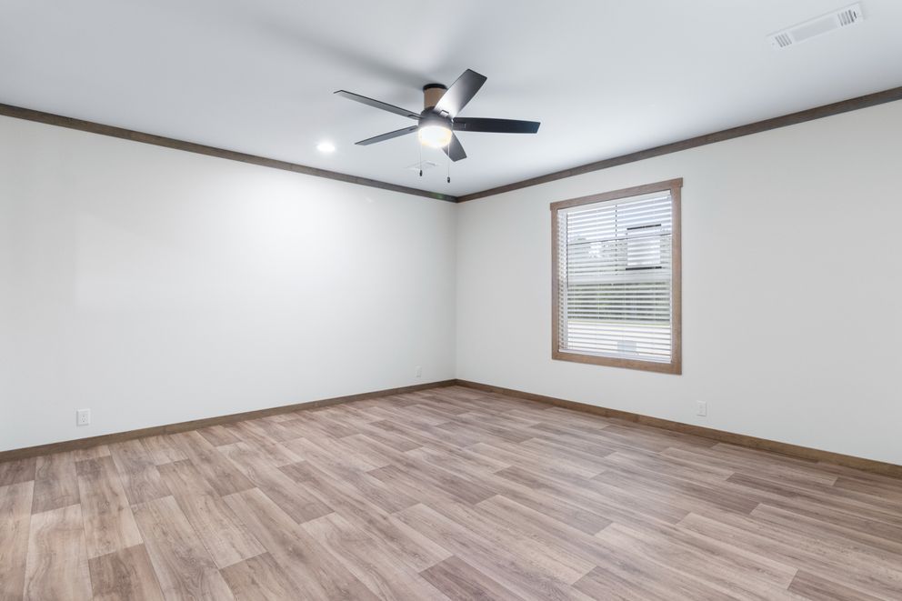 Empty room with wood-look floor, white walls, ceiling fan, and one window with blinds