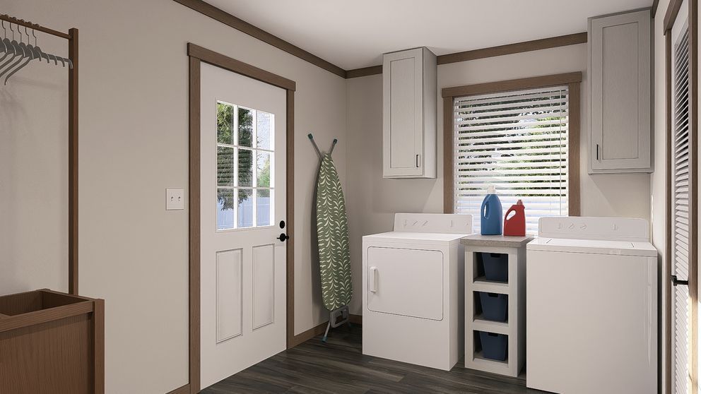 Small laundry room with white cabinets, washer-dryer, sink, and a door with an ironing board nearby.
