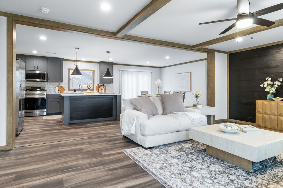 Modern open-plan living room with white sofa, coffee table, kitchen island, and ceiling fan