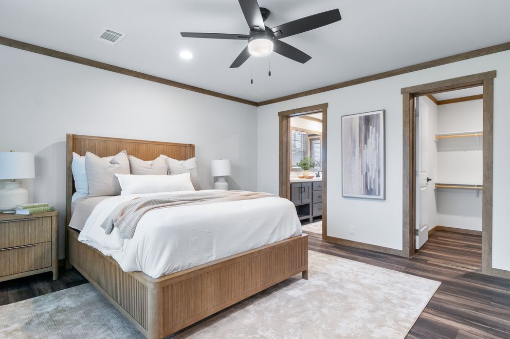 Bright bedroom with a wooden bed, nightstands, ceiling fan, and open closet doors.