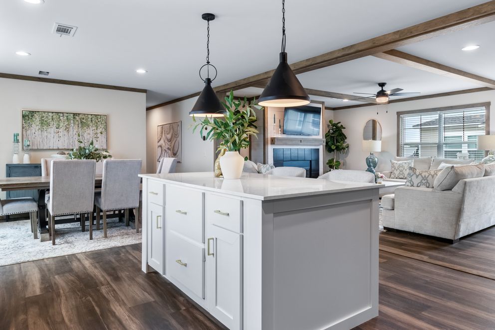 Open-concept modern living room and kitchen with white island, dark wood floors, and pendant lights