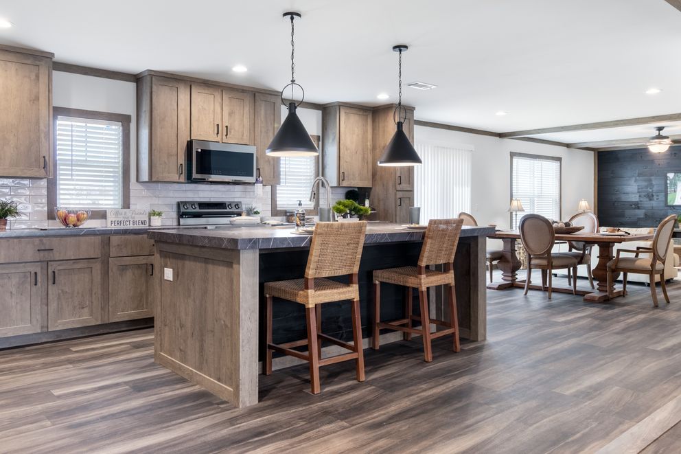 Modern kitchen with wooden cabinets, island seating, and a dining area in an open floor plan.