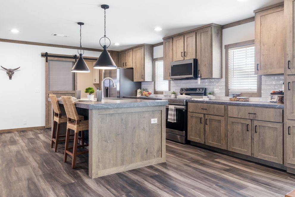 Modern kitchen with wood cabinets, island seating, pendant lights, and stainless steel appliances