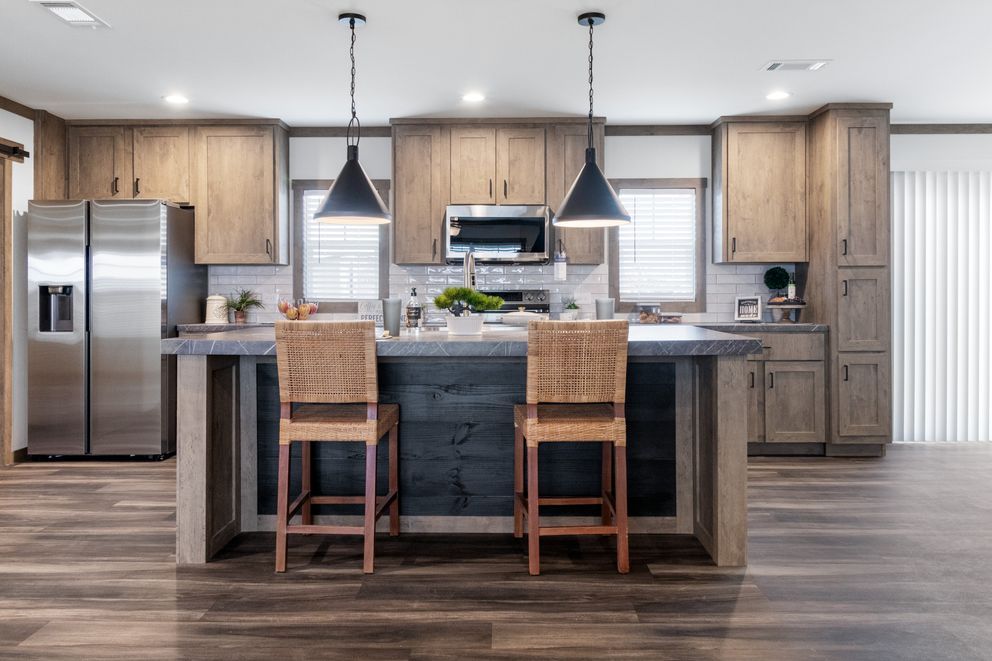 Modern kitchen with stainless steel appliances, wood cabinets, island seating, and pendant lights