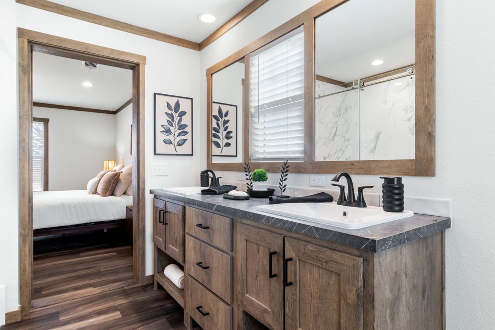 Modern bathroom vanity with wood cabinets, black fixtures, and large mirror in a bright hallway bathroom