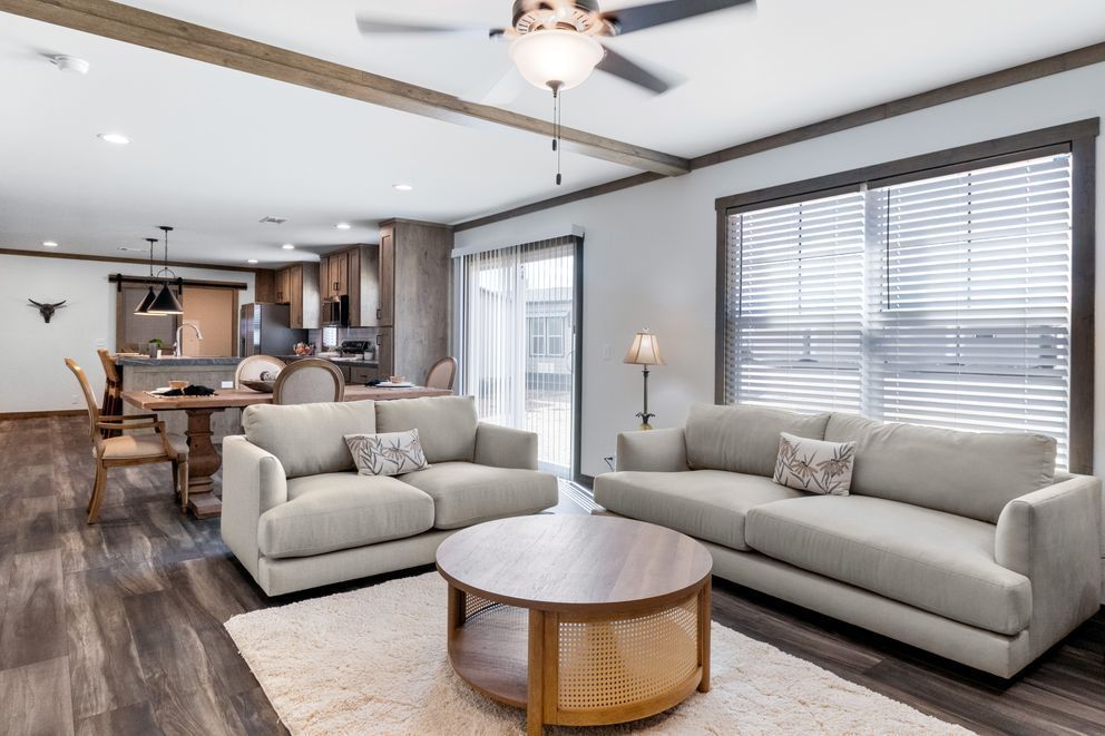 Modern living room with two gray sofas, round coffee table, and open kitchen in the background