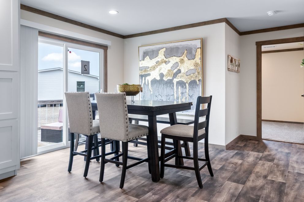 Modern dining area with a round table, four chairs, and abstract wall art near large windows.