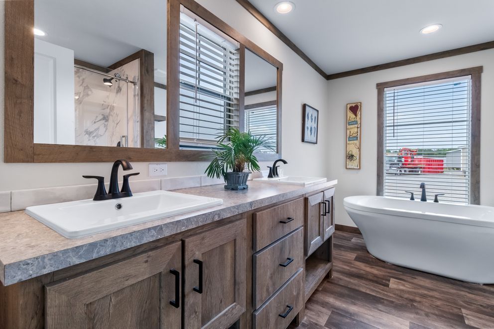 Modern bathroom with double vanity, freestanding tub, wood accents, and large windows