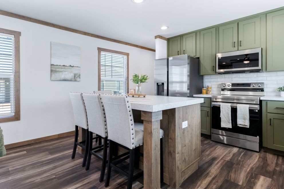 Modern kitchen with island, stainless steel appliances, green cabinets, and dark wood floors