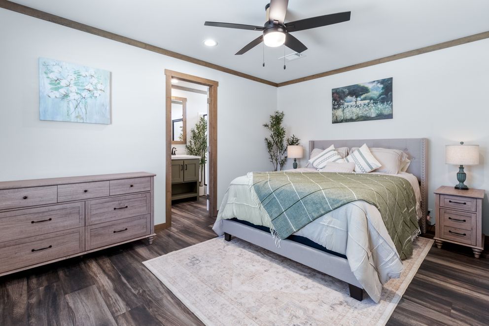 Modern bedroom with gray bed, wood dresser, ceiling fan, and soft blue decor