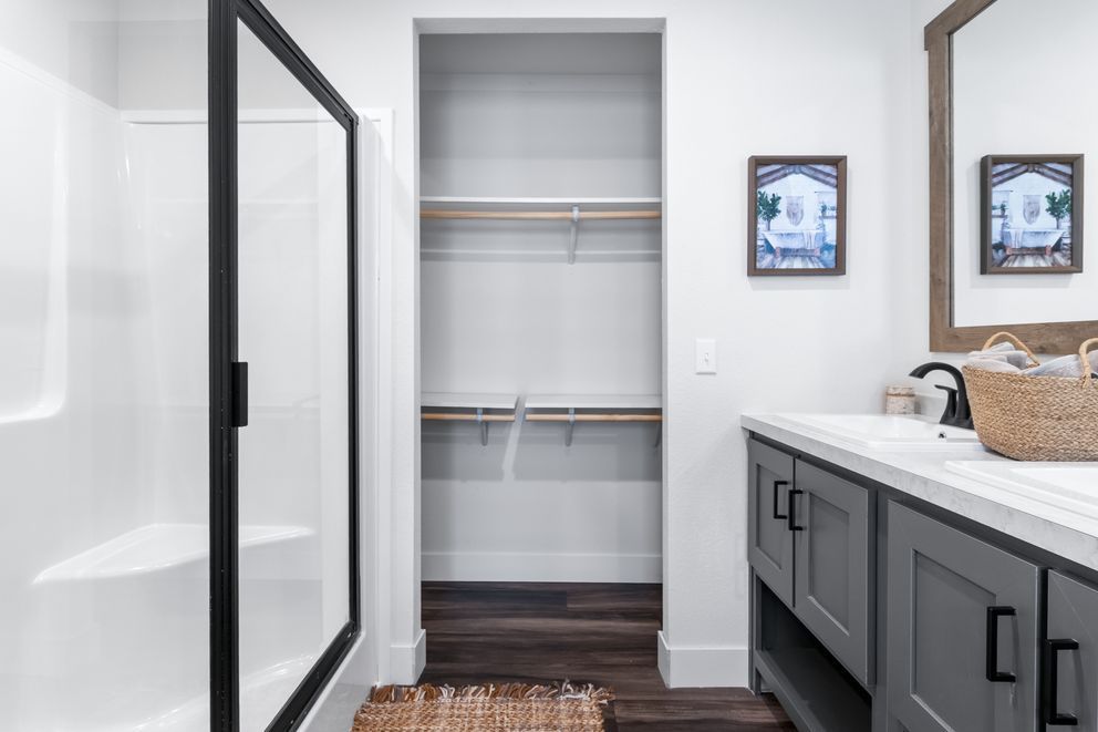 Modern bathroom with walk-in shower, open closet, and double vanity with mirrors