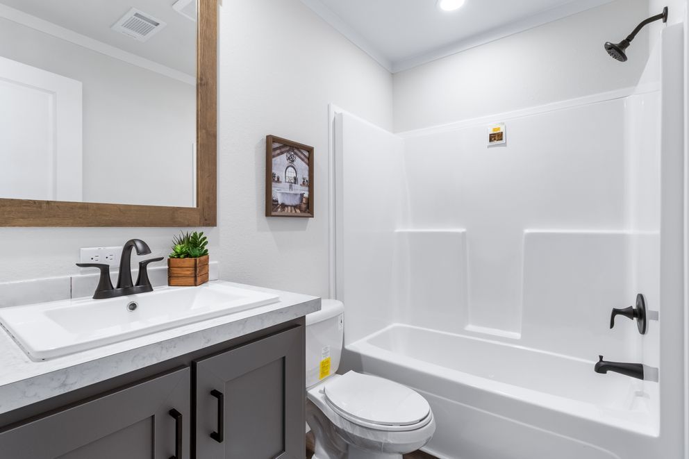 Small white bathroom with vanity, toilet, and bathtub with black fixtures